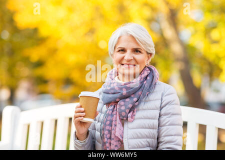 Ältere Frau trinkt Kaffee im Herbst Park Stockfoto