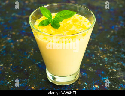 Vanille Mousse oder Pudding mit Zitronenschale und Minze im Glas hohes Glas auf einem dunkelblauen Hintergrund. Close-up. Stockfoto