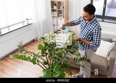 Mann spritzen Zimmerpflanze mit Wasser zu Hause Stockfoto