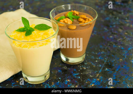 Dessert Schokoladenpudding mit Muttern und Vanillepudding mit Zitronenschale auf einem Holztisch Stockfoto