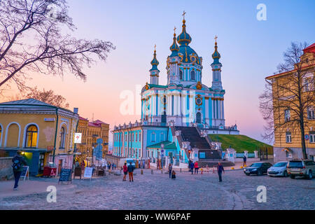 KIEW, UKRAINE - 13. APRIL 2018: Der wunderschöne Blick auf die St. Andrew Kirche auf dem Hügel und die historischen Gebäude von Andrews Abstieg in hellen dämmerungen Stockfoto
