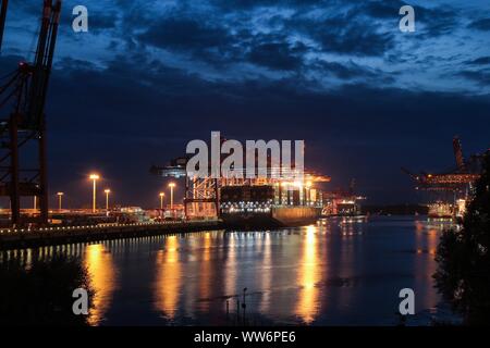 HAMBURG, AUGUST 2013: Beleuchtete Containerschiff/Frachter in der Nacht (Magic Hour) im Hamburger Hafen mit großen Portalkränen (Container Krane). B Stockfoto