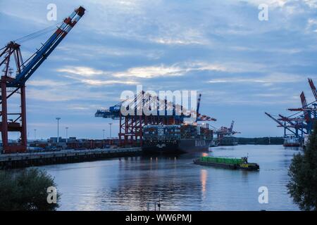 HAMBURG, AUGUST 2013: ein Container Feeder Schiff reisen, vorbei an einem riesigen Containerschiff während der Dämmerung im Hamburger Hafen. Schuß auf Rot. Stockfoto