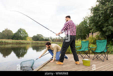 Männliche Freunde mit Net und Angeln auf dem See Stockfoto