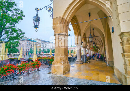 Krakau, Polen - Juni, 13, 2018: Die malerische Arcade der Tuchhallen (Sukiennice) ist mit Tischen der Restaurants mit Blick auf den Hauptmarkt belegt Stockfoto