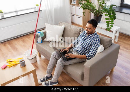 Mann mit Laptop nach Hause Reinigung Stockfoto