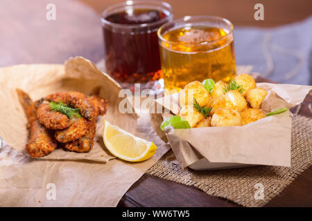Bier Snacks. Gebratene gebratener Fisch und Käse Kugeln mit Zitrone und Grüns. Snacks, verschiedene Biere. Stockfoto