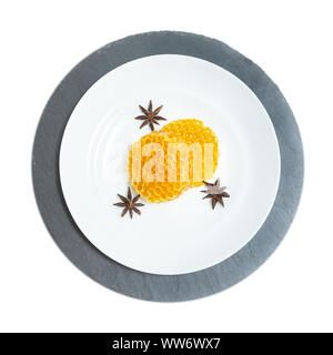 Runde Waben liegen auf einer Platte auf einem weißen Holz- Hintergrund. Stockfoto