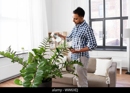 Mann spritzen Zimmerpflanze mit Wasser zu Hause Stockfoto