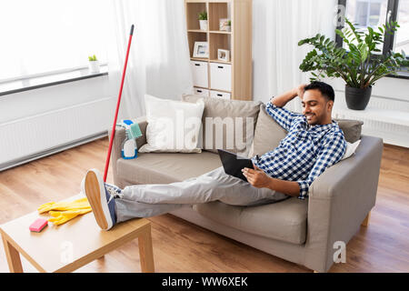 Mann mit Tablet Computer nach Hause Reinigung Stockfoto