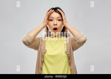 Asiatische Frau mit zu ihrem Kopf schockiert Stockfoto