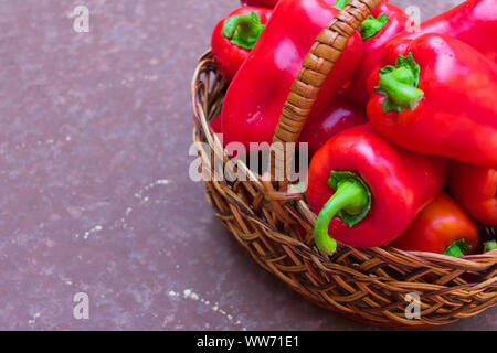 Rot (süß) Paprika in einem Weidenkorb auf braunem Grund. Kopieren Sie Platz. Ansicht von oben. Stockfoto