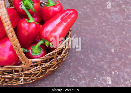 Rot (süß) Paprika in einem Weidenkorb auf braunem Grund. Kopieren Sie Platz. Ansicht von oben. Stockfoto