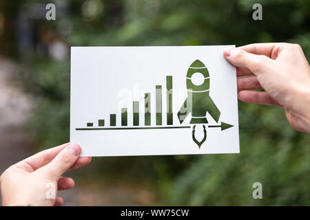 Hände, die Papier mit Ausschnitt Wachstumsdiagramm im Freien Stockfoto