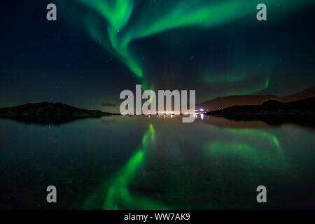 Grün Nordlicht in den See mit den Bergen und der Stadt im Hintergrund, Nuuk, Grönland widerspiegelt Stockfoto