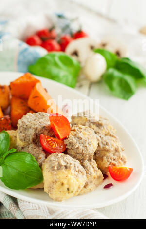 Huhn Fleischbällchen in Pilzsauce mit Süßkartoffeln, Tomaten und frischem Basilikum Blätter serviert. Stockfoto