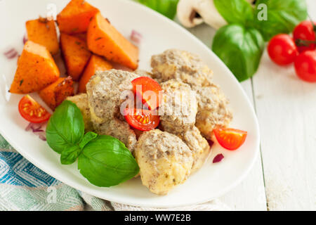 Huhn Fleischbällchen in Pilzsauce mit Süßkartoffeln, Tomaten und frischem Basilikum Blätter serviert. Stockfoto