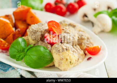 Huhn Fleischbällchen in Pilzsauce mit Süßkartoffeln, Tomaten und frischem Basilikum Blätter serviert. Stockfoto