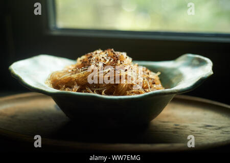 Cellophan mit Sesamsamen mit süßer und saurer Soße.in einer tiefen Keramikschale handgefertigt. Appetitliches Gericht. Stockfoto