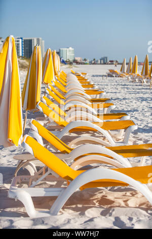 Leere weiße und gelbe Plastikliegen und Sonnenschirme in Clearwater Beach, Florida, USA. Stockfoto