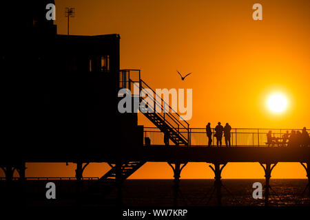 Aberystwyth Wales UK, Freitag 13 September 2019 Leute stehen an der viktorianischen Badeort von Aberystwyth Pier ab, als sie die letzten Strahlen der Sonnen zusehen, wie es über die Cardigan Bay, auf eine glorreiche Anfang Herbst abends, am Wochenende wird erwartet, warm mit Temperaturen in der Mitte 20 Celsius in Teilen der Südosten der UK Photo credit Keith Morris/Alamy Leben Nachrichten beigelegt werden Stockfoto