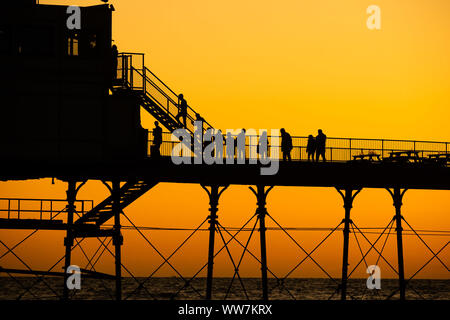 Aberystwyth Wales UK, Freitag 13 September 2019 Leute stehen an der viktorianischen Badeort von Aberystwyth Pier ab, als sie die letzten Strahlen der Sonnen zusehen, wie es über die Cardigan Bay, auf eine glorreiche Anfang Herbst abends, am Wochenende wird erwartet, warm mit Temperaturen in der Mitte 20 Celsius in Teilen der Südosten der UK Photo credit Keith Morris/Alamy Leben Nachrichten beigelegt werden Stockfoto