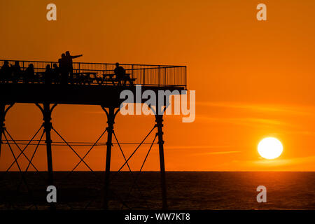 Aberystwyth Wales UK, Freitag 13 September 2019 Leute stehen an der viktorianischen Badeort von Aberystwyth Pier ab, als sie die letzten Strahlen der Sonnen zusehen, wie es über die Cardigan Bay, auf eine glorreiche Anfang Herbst abends, am Wochenende wird erwartet, warm mit Temperaturen in der Mitte 20 Celsius in Teilen der Südosten der UK Photo credit Keith Morris/Alamy Leben Nachrichten beigelegt werden Stockfoto