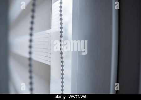 Details der weißen Stoff rollos auf dem weißen Kunststoff Fenster im Wohnzimmer. Nahaufnahme auf Rolle Vorhänge indoor. Stockfoto