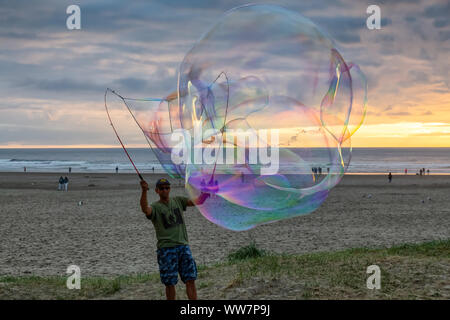 Seaside, Oregon, USA - September 6, 2019: Der Mensch, der grosse Seifenblasen am Sandstrand in einer dramatischen Sommer Sonnenuntergang. Stockfoto