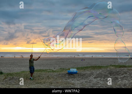 Seaside, Oregon, USA - September 6, 2019: Der Mensch, der grosse Seifenblasen am Sandstrand in einer dramatischen Sommer Sonnenuntergang. Stockfoto