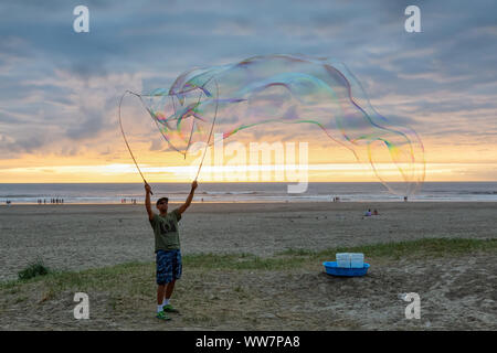 Seaside, Oregon, USA - September 6, 2019: Der Mensch, der grosse Seifenblasen am Sandstrand in einer dramatischen Sommer Sonnenuntergang. Stockfoto