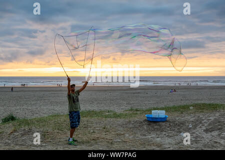 Seaside, Oregon, USA - September 6, 2019: Der Mensch, der grosse Seifenblasen am Sandstrand in einer dramatischen Sommer Sonnenuntergang. Stockfoto