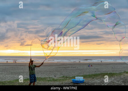 Seaside, Oregon, USA - September 6, 2019: Der Mensch, der grosse Seifenblasen am Sandstrand in einer dramatischen Sommer Sonnenuntergang. Stockfoto