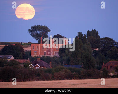 Eastchurch, Kent, Großbritannien. 13. September, 2019. UK Wetter: Die vollständige Harvest Moon gesehen steigende über historische Shurland Halle (wo Henry VIII seine Flitterwochen verbracht) in Eastchurch, Kent an diesem Abend. Credit: James Bell/Alamy leben Nachrichten Stockfoto