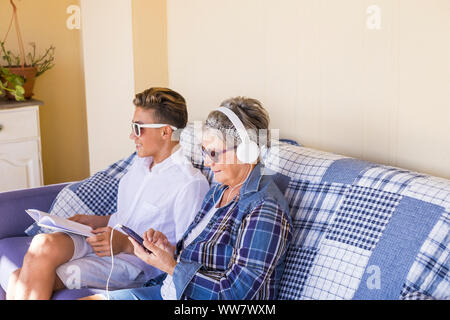 Paar junge und alte Großmutter und Teenager Neffe Familie Zeit zusammen Musik hören mit Kopfhörern und den Tag genießen. Glückliche Familie und Generationen verschiedene Altersgruppen Konzept Stockfoto