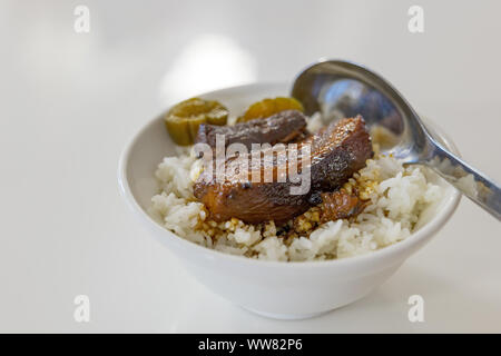 Nahaufnahme des Lu Rou Ventilator, Taiwanesische langsam kochen Sojasauce geschmorten Schweinebauch, mit Reis in der kleinen weißen Schale und weißer Tisch. Stockfoto