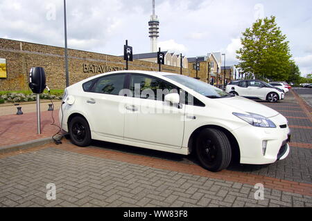 Lelystad, Niederlande - 1 September, 2019: Weiße Toyota Prius auf einem öffentlichen Parkplatz aufgeladen wird. Niemand im Fahrzeug. Stockfoto