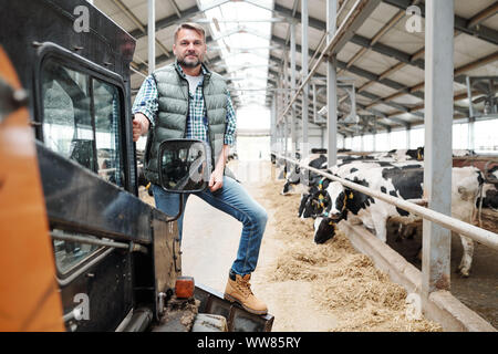 Männliche Arbeiter der Farm der Tiere zu Ihnen schauen beim Stehen auf Arbeitsmittel Stockfoto