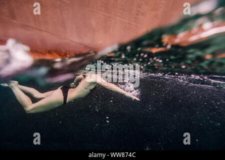 Volle Länge des Frau Schwimmen im Ozean in der Nähe der Yacht Stockfoto