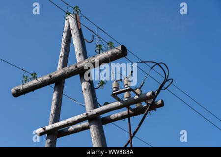 Die Verteilung von Strom, high-voltage power Pole mit Drähten auf Isolatoren gegen klare wolkenlosen blauen Himmel Stockfoto