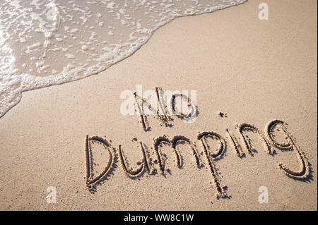 Kein Dumping Meer Verschmutzung Nachricht handschriftlich in einfachen Text auf glatten Sandstrand mit ankommenden Welle Stockfoto