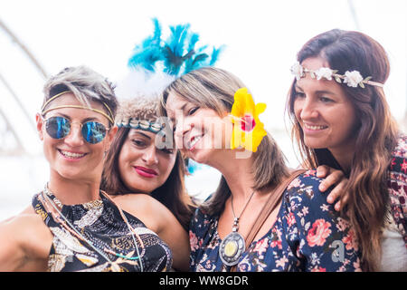 Vier freundliche junge schöne Frauen feiern zusammen und ein selfie Bild lächeln und Spaß in der Freundschaft nehmen, party Konzept mit farbigen Kleid und Blumen Masse, hellen Hintergrund, Menschen glücklich Stockfoto