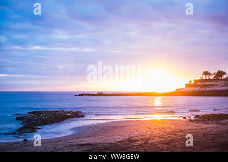 Erstaunlich schöne zeitlose Sonnenuntergang am Strand mit Blick aufs Meer und Palmen im Hintergrund, schöne Farben von orange bis tiefblau, Entspannen und Sommerurlaub Konzept Stockfoto