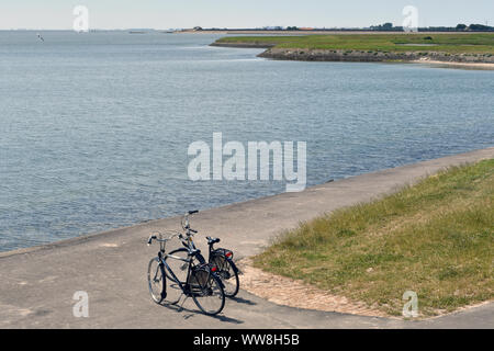 Zwei Fahrräder parkten auf einem gepflasterten Weg an der Küste Der Insel Texel mit der Nordsee vor Der Fahrräder Stockfoto