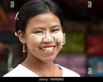 Die jungen burmesischen Frau mit Patches von gelblich-weißes, traditionelles thanaka Gesicht Kosmetik auf der Nase und Wangen, Lächeln für die Kamera. Stockfoto