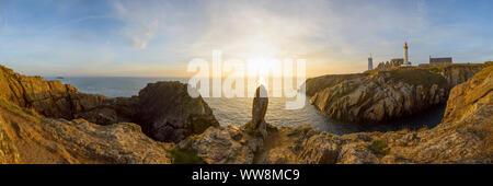 Bucht mit Monolith und Leuchtturm bei Sonnenuntergang, Saint Mathieu Leuchtturm Pointe Saint-Mathieu, Plougonvelin, Finistère, Bretagne, Frankreich Stockfoto