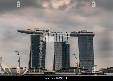 Singapur - März 20, 2019: Marina Bay Sands Hotel und Casino mit seinen drei Türmen unter regnerischen Schwere cloudscape. Weißes Oberteil wie Struktur ist Kunst - Sc Stockfoto