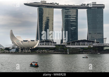 Singapur - März 20, 2019: Marina Bay Sands Hotel und Casino mit seinen drei Türmen von hinter der Bucht unter regnerischen Schwere cloudscape gesehen. Weißes Oberteil ist Stockfoto