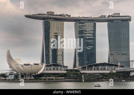 Singapur - März 20, 2019: Marina Bay Sands Hotel und Casino mit seinen drei Türmen von hinter der Bucht unter regnerischen Schwere cloudscape gesehen. Weißes Oberteil ist Stockfoto