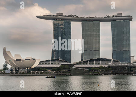 Singapur - März 20, 2019: Marina Bay Sands Hotel und Casino mit seinen drei Türmen von hinter der Bucht unter regnerischen Schwere cloudscape gesehen. Weißes Oberteil ist Stockfoto